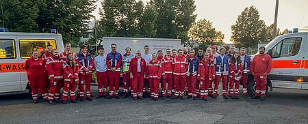 Gruppen Bild mit Einsatzkräften der Wasserwacht, die vor ihren Fahrzeugen stehen